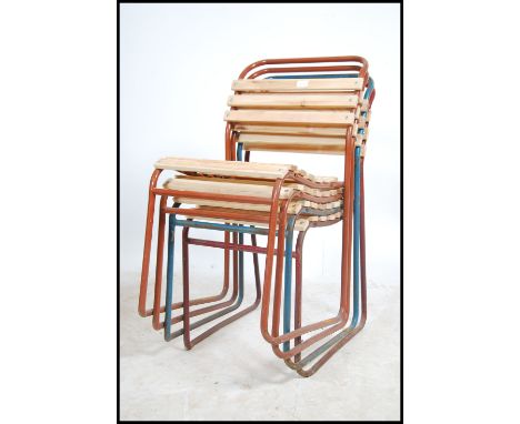 A stack of vintage mid century Industrial / school hall stacking chairs being raised on tubular metal frames with recently ne