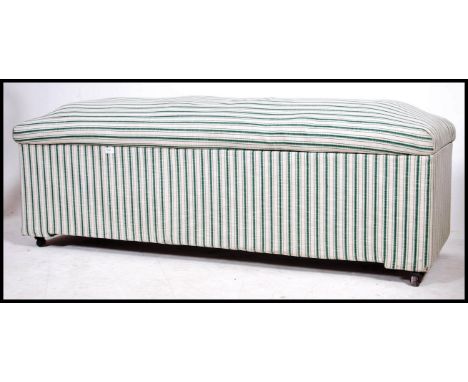A large early 20th century linen lined ottoman of rectangular form having button backed cushion top with castors to the base.
