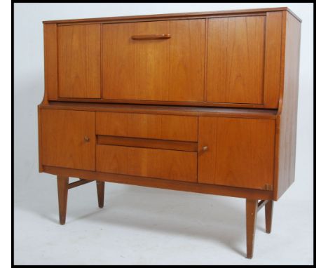 A vintage mid 20th century teak sideboard credenza, two cupboards over two drawers. The drinks cabinet opening with metamorph