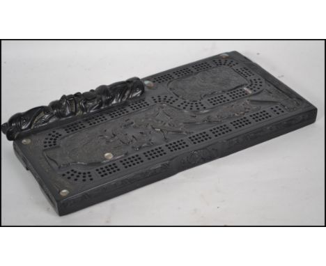 A cribbage board in the Haida native american style with totemic decoration and haliotis shell inlaid panels dating to the 20