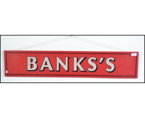 A vintage 20th century Banks Brewery enamel metal sign having white lettering on a red background. Measures 100cms wide by 20