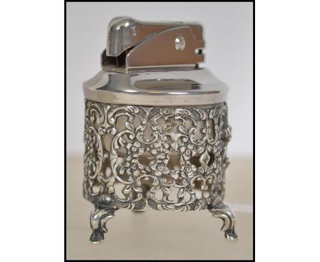 A silver 850 cased table lighter of cylindrical rococo form being raised on hoof feet. Total weight 59.6g. Measures 6cm high.