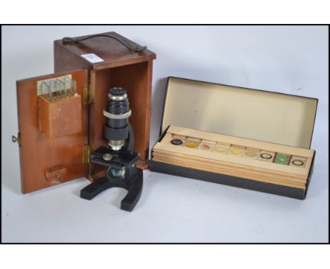 A vintage cased microscope together with a box of scientific glass slides dating from the early 20th century. Measures 20cm h