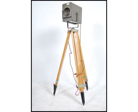 A mid century Industrial Strand Theatre cinema light of metal form with original grey paint being mounted to a wooden tripod 