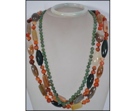 A green jade bead necklace having a barrel clasp along with a pale jade bangle bracelet and a large jadeite necklace. Necklac