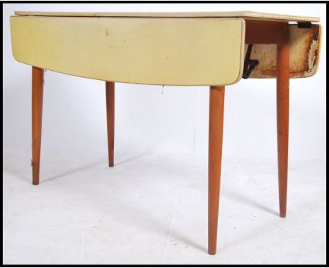 A vintage mid century large yellow formica and beech wood drop leaf dining - kitchenette table being raised on tapered legs w