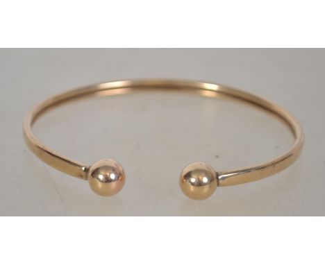 A 9ct gold ladies slave bangle - bracelet with ball finial ends having metal core. Total weight 5.5g