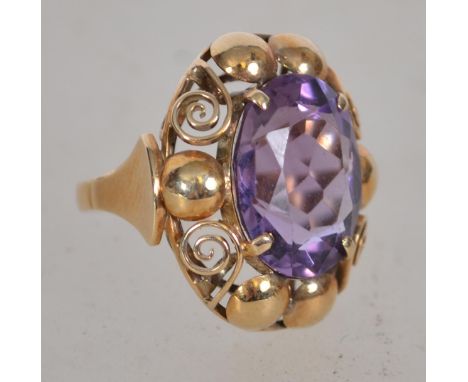 A believed Victorian 585 / 14ct gold and amethyst dress ring. The large oval amethyst being claw mounted with ball and scroll