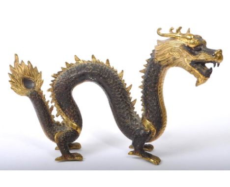A brass painted oriental Chinese dragon / loong figure with snake-like twisted body standing upon four feet. The scales paint