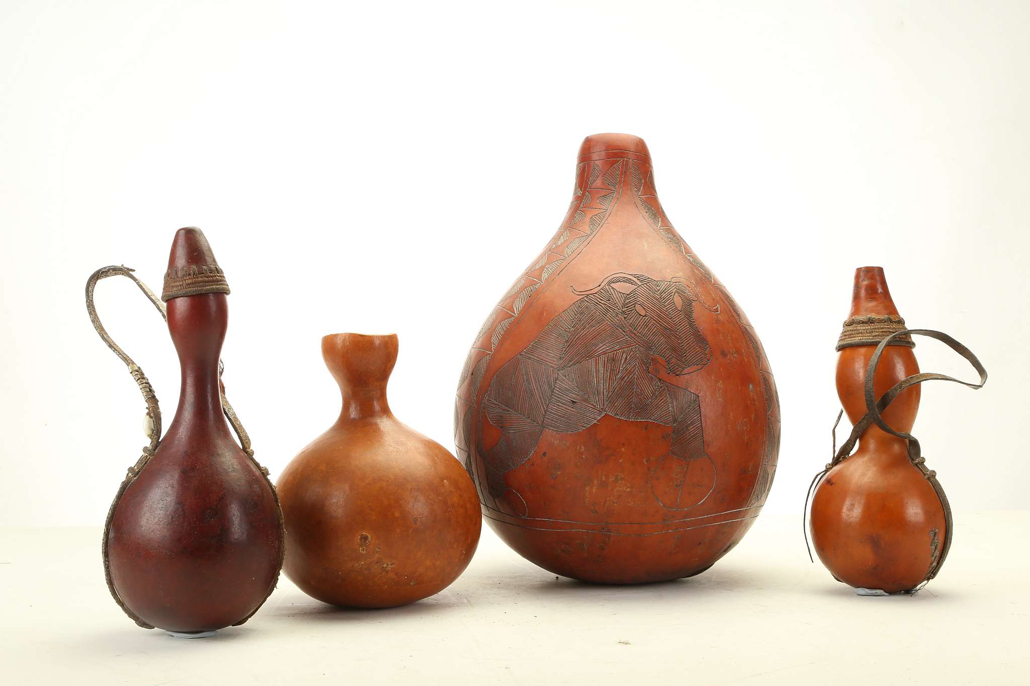 FOUR MASAI GOURD FLASKS, KENYA The largest a Kamba calabash decorated