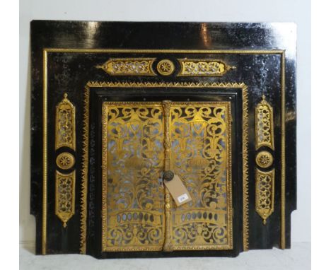 A late 19th Century Victorian ebonised Aesthetic Movement metal fire surround having pierced brass twin grilled doors
