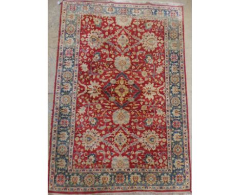 An Indian Agra carpet, the all over vine and palmette design on an abrashed terracotta ground within a turquoise border with 