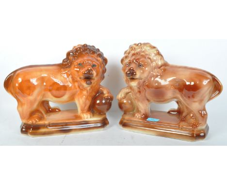 A pair of early 20th century Staffordshire style ceramic fireside mantel lion figures. Each modelled with glass eyes,&nbsp; p