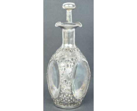 A vintage 20th century white metal and glass three sided whiskey bottle / decanter having pierced dragon motifs with stopper 