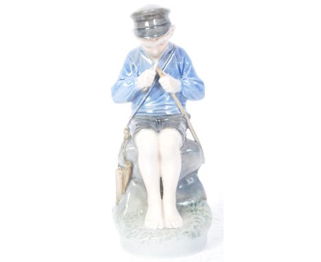 An early 20th century Royal Copenhagen porcelain figurine of a small seated boy whittling a stick. Stamped to the underside. 