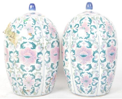 A pair of vintage 20th century Chinese ceramic lidded vases being hand painted with florals and blue finials to each lid. Mea