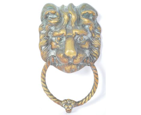 An early 20th century gilt metal door knocker in the form of a lions head holding ring knocker within mouth. Measures 20cm le