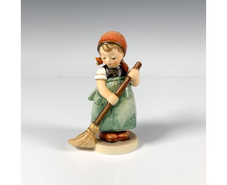 A small figure of a girl wearing a green apron decorated with a delicate floral pattern, a red scarf around her head and is h