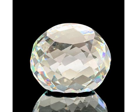 A clear crystal paperweight with a border of rectangular cuts and a smooth flat center that has a black swan imprint and text