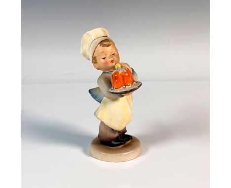 A young boy in a chefs hat and apron admiring the cake he just baked. M.I. Hummel impressed. Goebel backstamp. Artist: Arthur