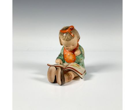 A small figure of a girl reading a book wearing a green dress with an orange bib and bow. Goebel backstamp. Issued: c. 1935Di