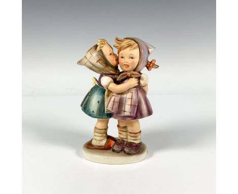 A figure of a girl whispering into her friends ear. Dressed in colorful attire with scarves around their head. M.I. Hummel im