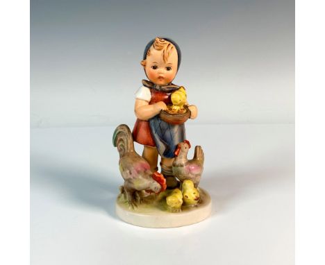 A colorful hand painted figure of a girl holding a bowl of grains to feed her chickens and baby chicks. M.I. Hummel impressed