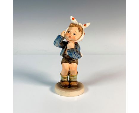 A distressed boy who is wearing a plaid blue jacket and a polka-dotted scarf around his head. M.I. Hummel impressed. Goebel b