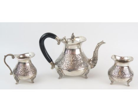 An Indian silver three-piece tea set, of squat ovoid form with chased floral decoration, on swept floral decorated feet, incl