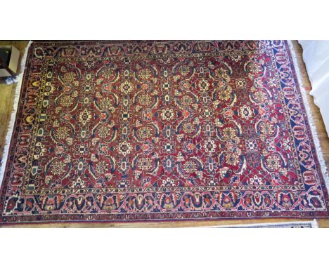 A Bakhtiari rug, the wine red field with four rows of flowerhead medallions, enclosed by a triple floral meander border, 320 