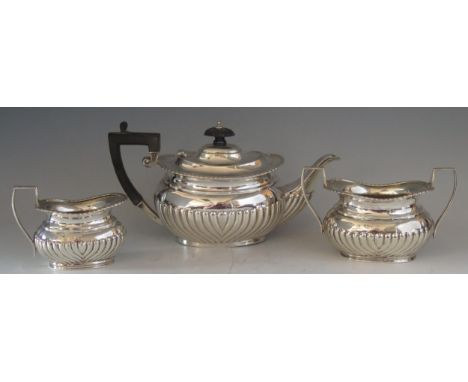 A matched silver three-piece tea service, various makers and dates, of barge-shaped outline with half reeded decoration, incl