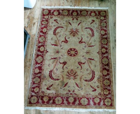 An Afghan Zeigler rug, the main beige field, with central wine red medallion, within trailing foliage, enclosed by a main win