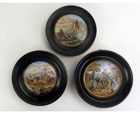 Three Prattware pot lids, 'The Village Wedding', 'Derby Day' and 'Mending the Nets' all in ebonised circular frames. 