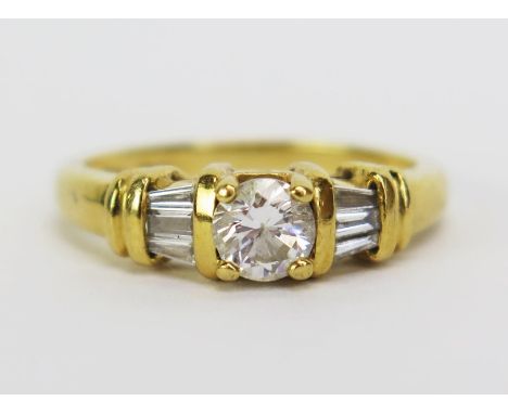 An 18ct Gold and Diamond Ring, the central 5mm stone shouldered by three 2.8mm baguette cut stones, stamped marks, size J.5, 
