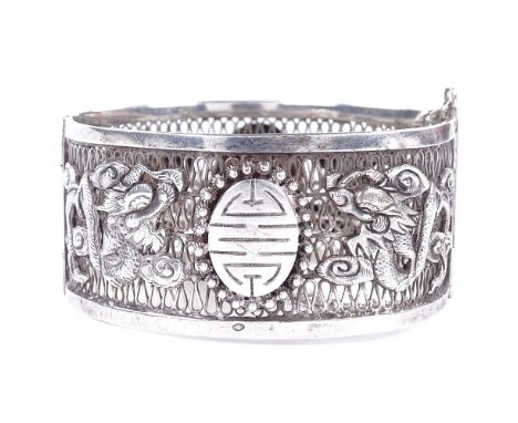 An Antique Chinese silver hinged bangle, openwork body with relief applied dragon decoration and central cannetille panel, ba