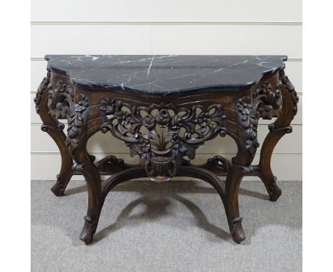 An ornate Rococo style carved walnut console table with shaped marble top, carved and pierced floral frieze and carved base, 