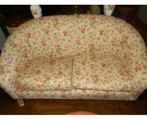 A Laura Ashley two-seater sofa, having floral upholstery, raised on four turned legs.