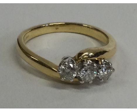 A three stone cross over ring in 18 carat gold mount. Approx. 4 grams. Est. £100 - £150.