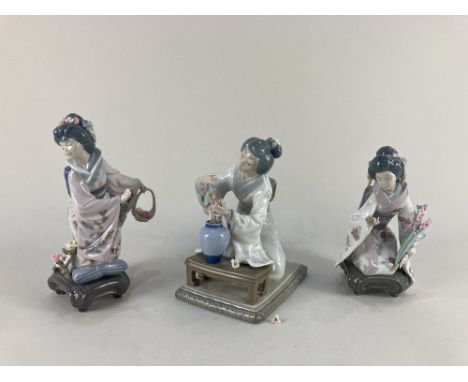 A pair of Lladro porcelain figures of Japanese geishas kneeling and holding flowers, together with a another Lladro figure of