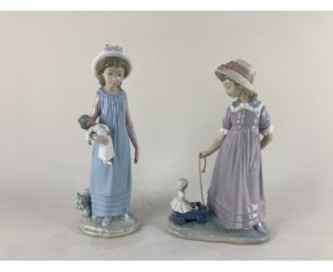 Two Lladro porcelain figures of girls, one playing with a doll, the other pulling a truck containing a doll, tallest 29cm hig
