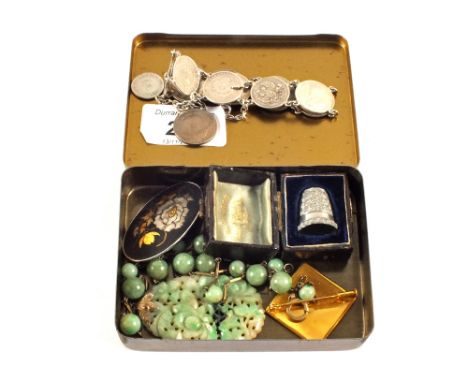 A Silver bracelet made up of coins, a Silver cased thimble, Jade necklace and two Japanese brooches