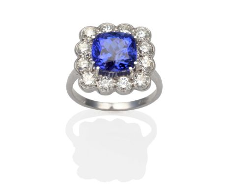 A Tanzanite and Diamond Cluster Ring, a cushion cut tanzanite in a white claw setting within a border of round brilliant cut 