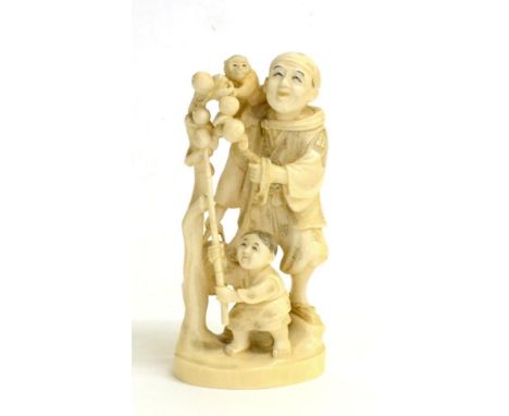 A Japanese Ivory Okimono of a Street Entertainer, Meiji period, standing, a monkey on his shoulder, a child holding a stick w