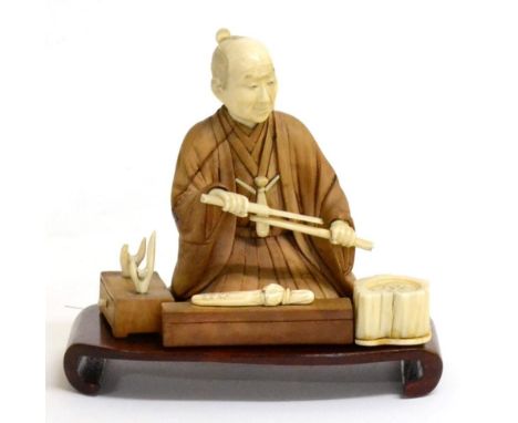 A Japanese Ivory, Hardwood and Mother-of-Pearl Okimono, Meiji period, as a sword maker kneeling at his workbench holding a wa