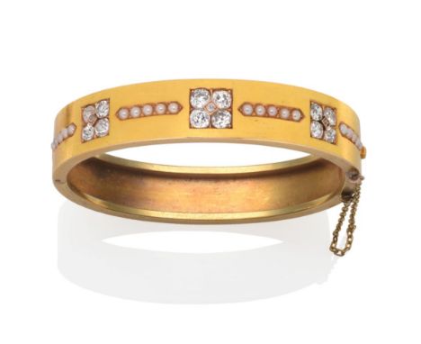 A Diamond and Seed Pearl Bangle, inset with three clusters of five old cut diamonds in yellow claw settings, spaced by rows o