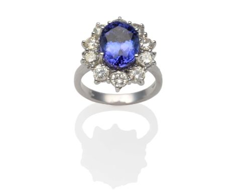 An 18 Carat White Gold Tanzanite and Diamond Cluster Ring, an oval cut tanzanite within a border of round brilliant cut diamo
