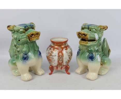 A pair of ceramic Buddhist lions, approximately 22 cm (h) and a Japanese vase raised on tripod supports.
