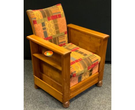 A 1930s Art Deco oak arm chair, each side with magazine holders, the front detaching into a folding foot stool, 79cm high. 