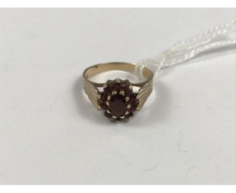 A 9ct gold and garnet dress ring, in a flower-head cluster arrangement over a radially-cut 9ct gold shank