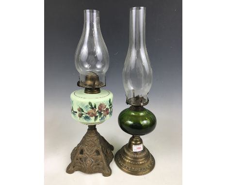 A cast and emerald green glass oil lamp together with one other similar